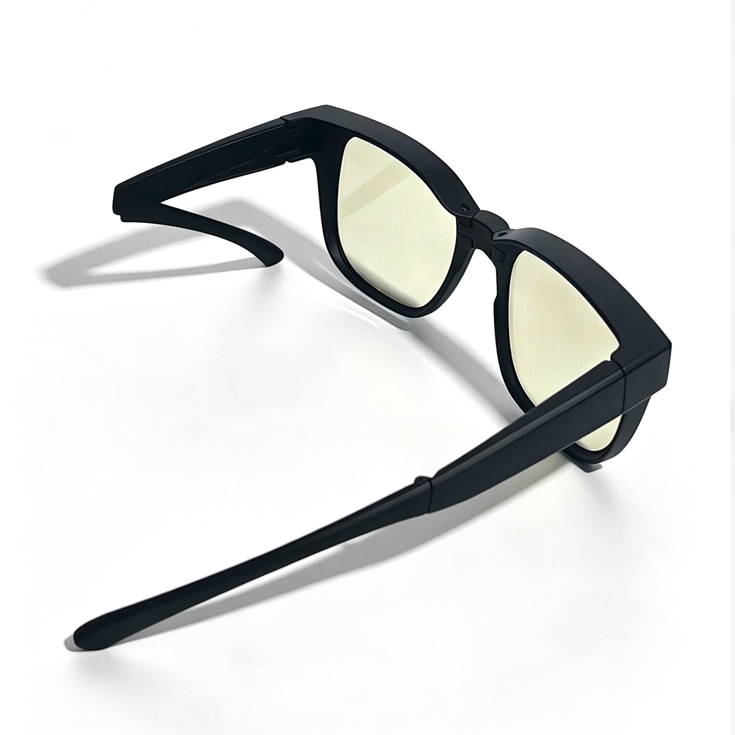 Matte black fit-over night driving glasses with light yellow lenses and one folding temple arm.
