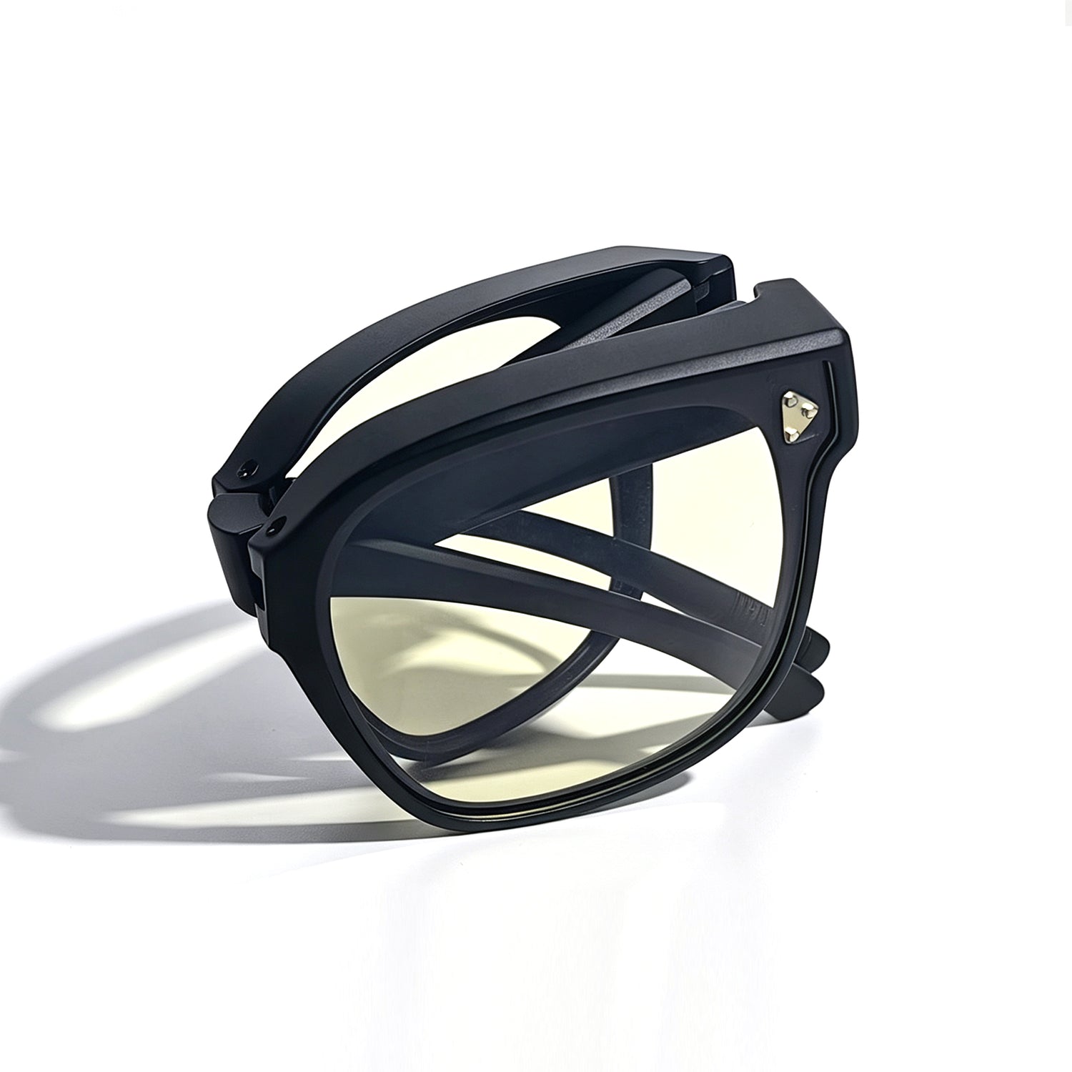 Fully folded matte black fit-over night driving glasses with light yellow lenses.