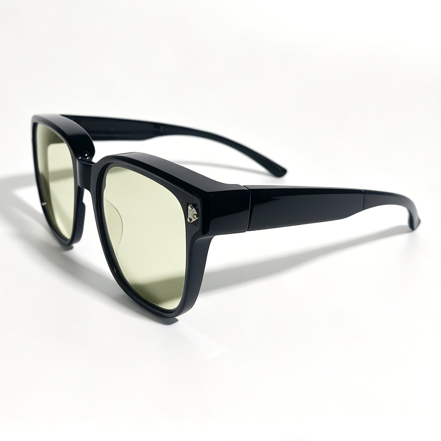 Glossy black fit-over night driving glasses with yellow-tinted lenses, shown from a front three-quarter angle.