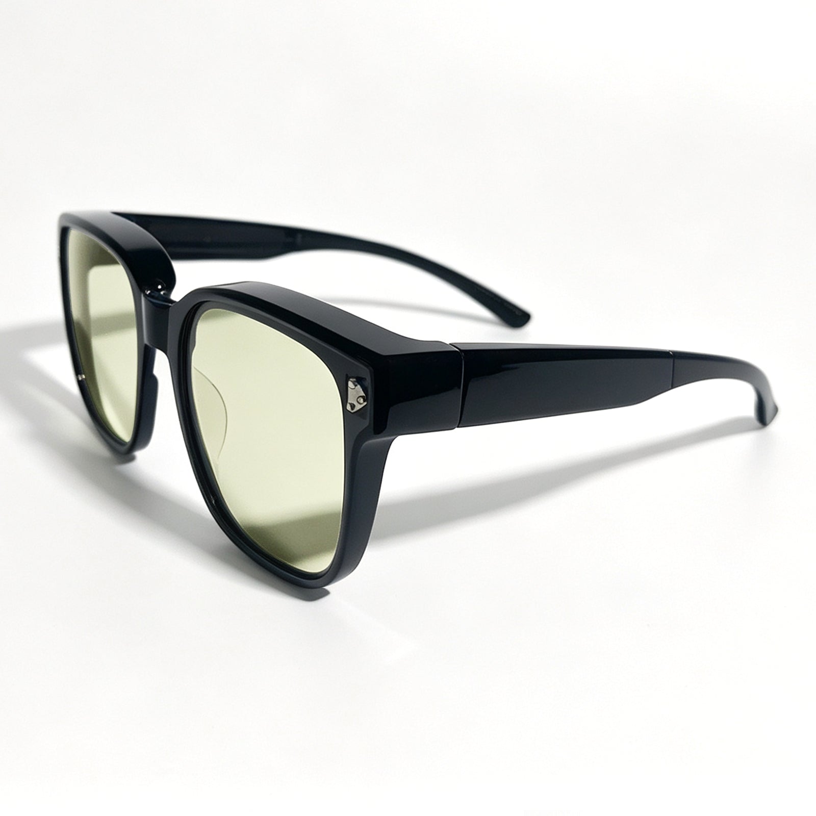 Glossy black fit-over night driving glasses with yellow-tinted lenses, shown from a front three-quarter angle.