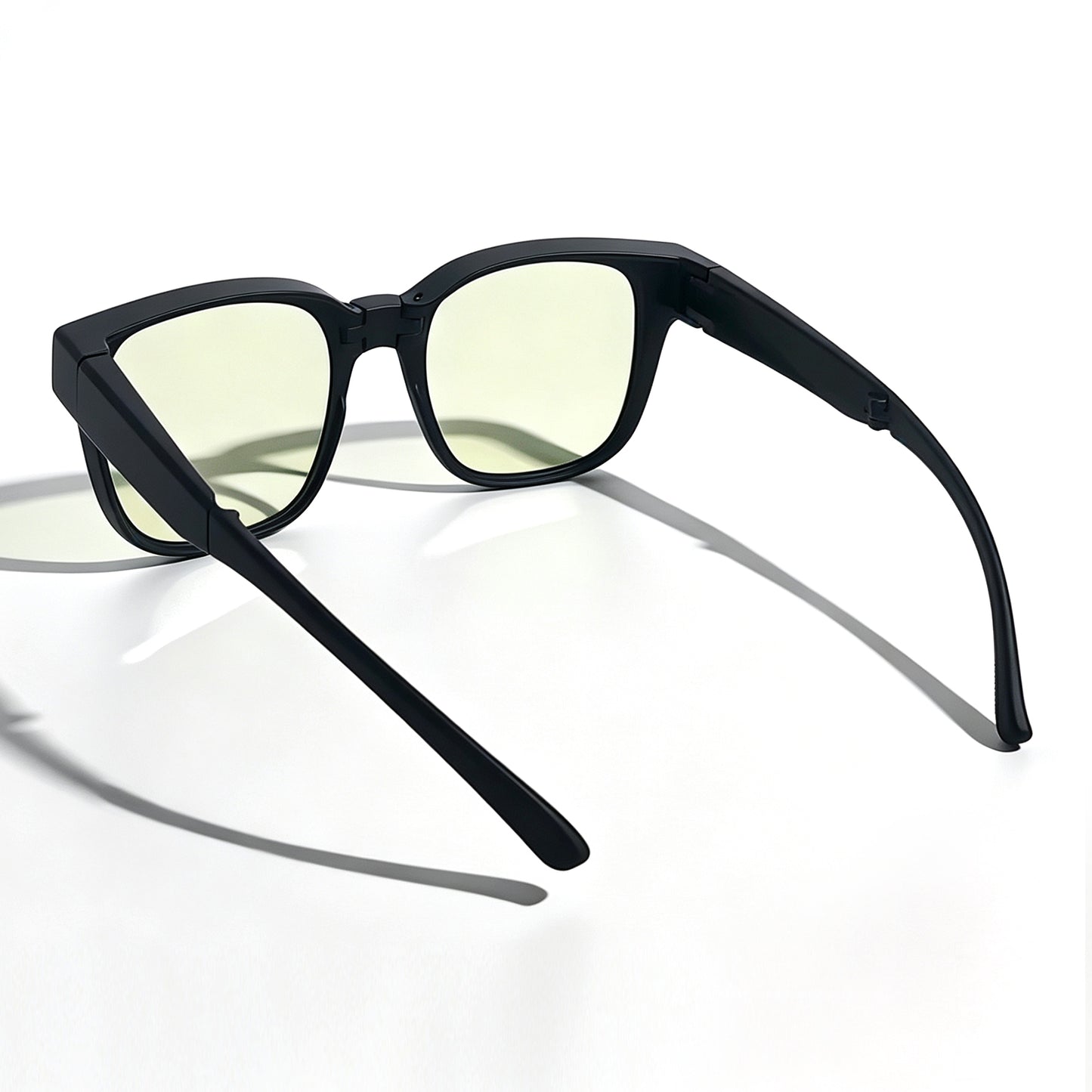Rear three-quarter view of matte black fit-over night driving glasses with light yellow lenses and flexible temple arms.