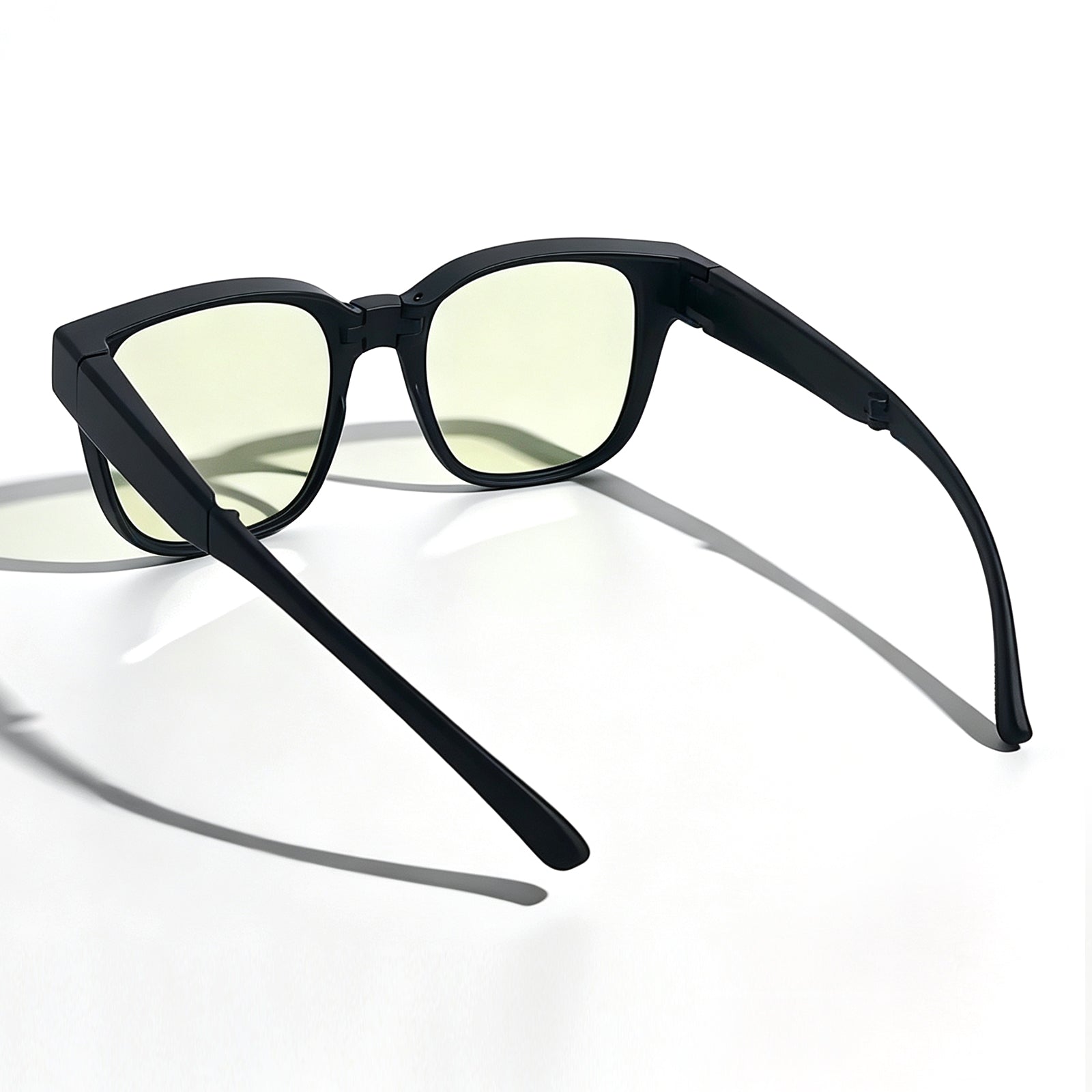 Rear three-quarter view of matte black fit-over night driving glasses with light yellow lenses and flexible temple arms.