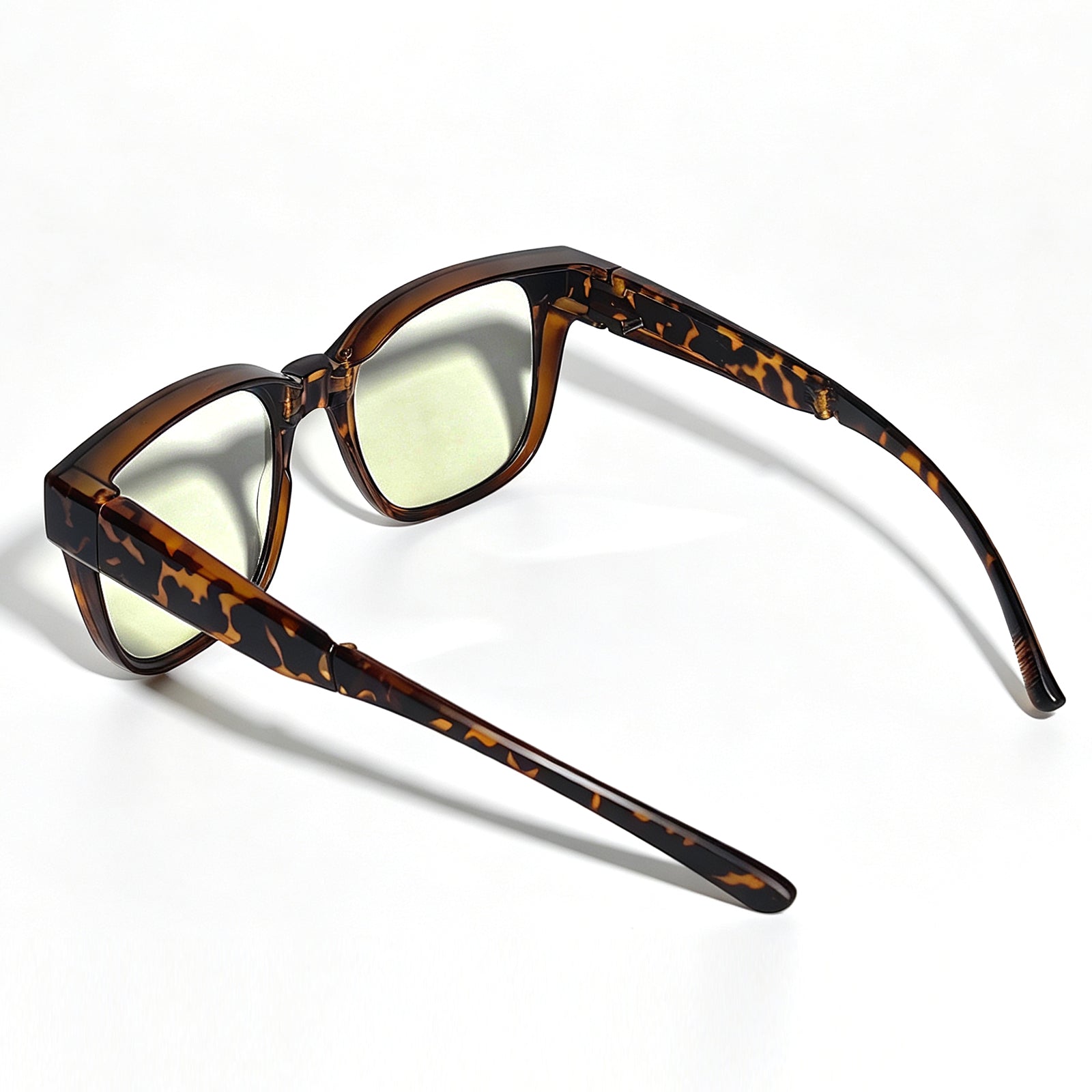 Tortoiseshell fit-over night driving glasses with yellow-tinted lenses, shown from a rear three-quarter angle with both temple arms fully extended.