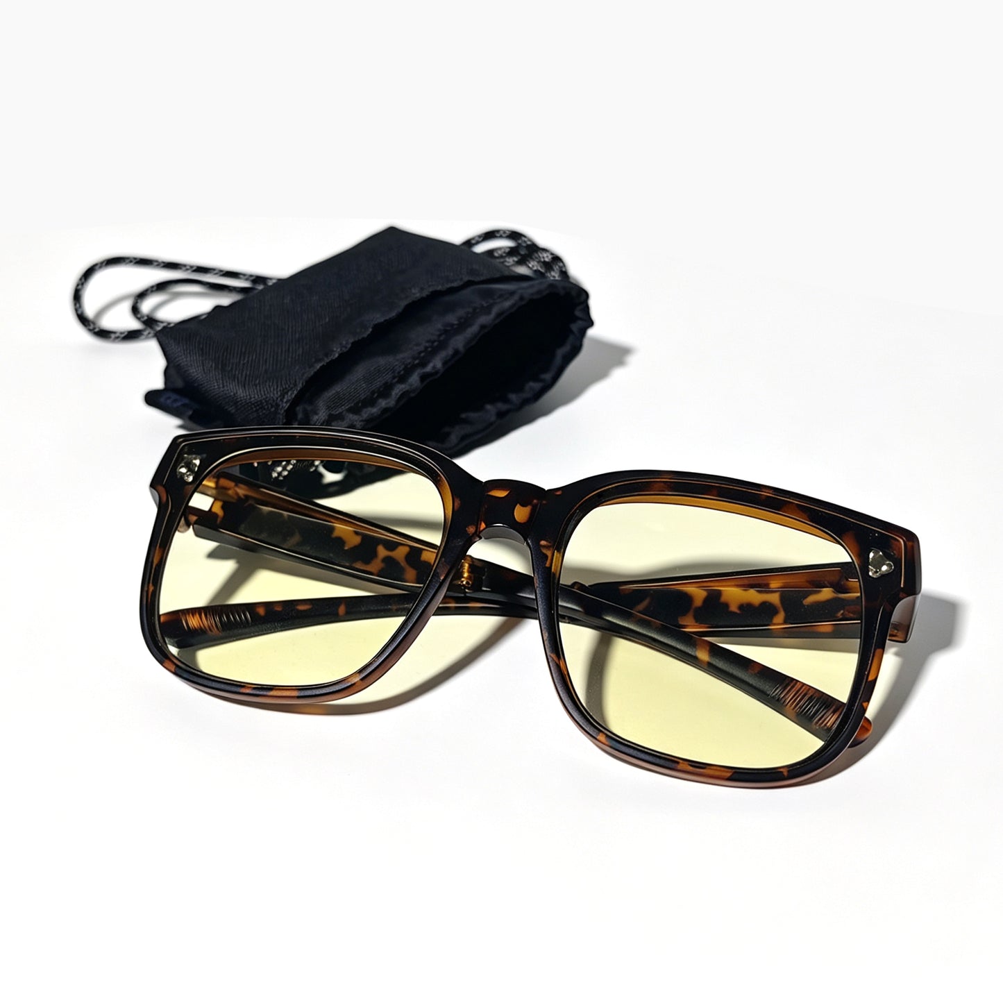 Tortoiseshell fit-over night driving glasses with yellow-tinted lenses shown beside a black drawstring storage pouch.